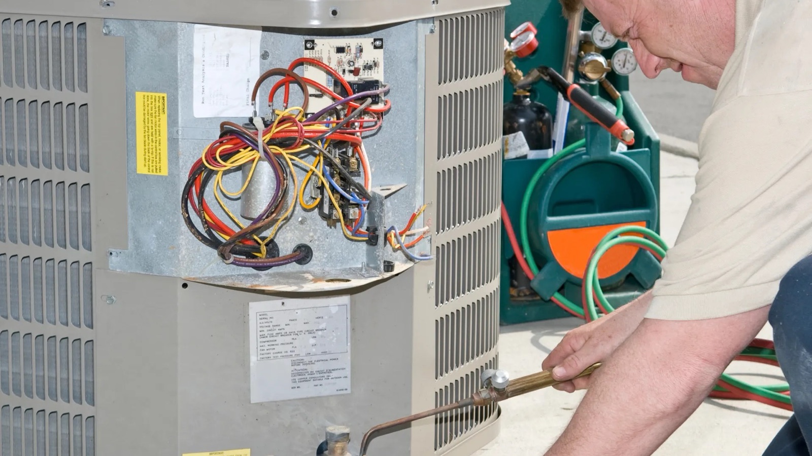Technician repairing an outdoor residential air-conditioning condenser